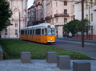 An orange tram of line 2 passing through a street in Budapest