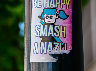 Sticker on a pole: Be happy, smash a nazi