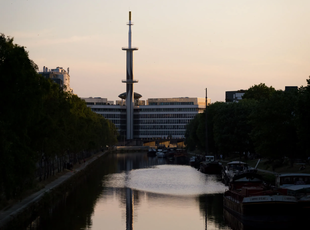 Building with a chimney seen behind a river