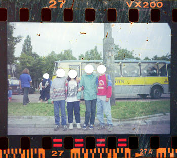 A group of kids posing for a small group photo in front of a bus
