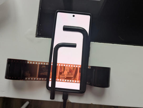 Pixel phone with white background, roll of film stretched across it and held in place with two large hex keys